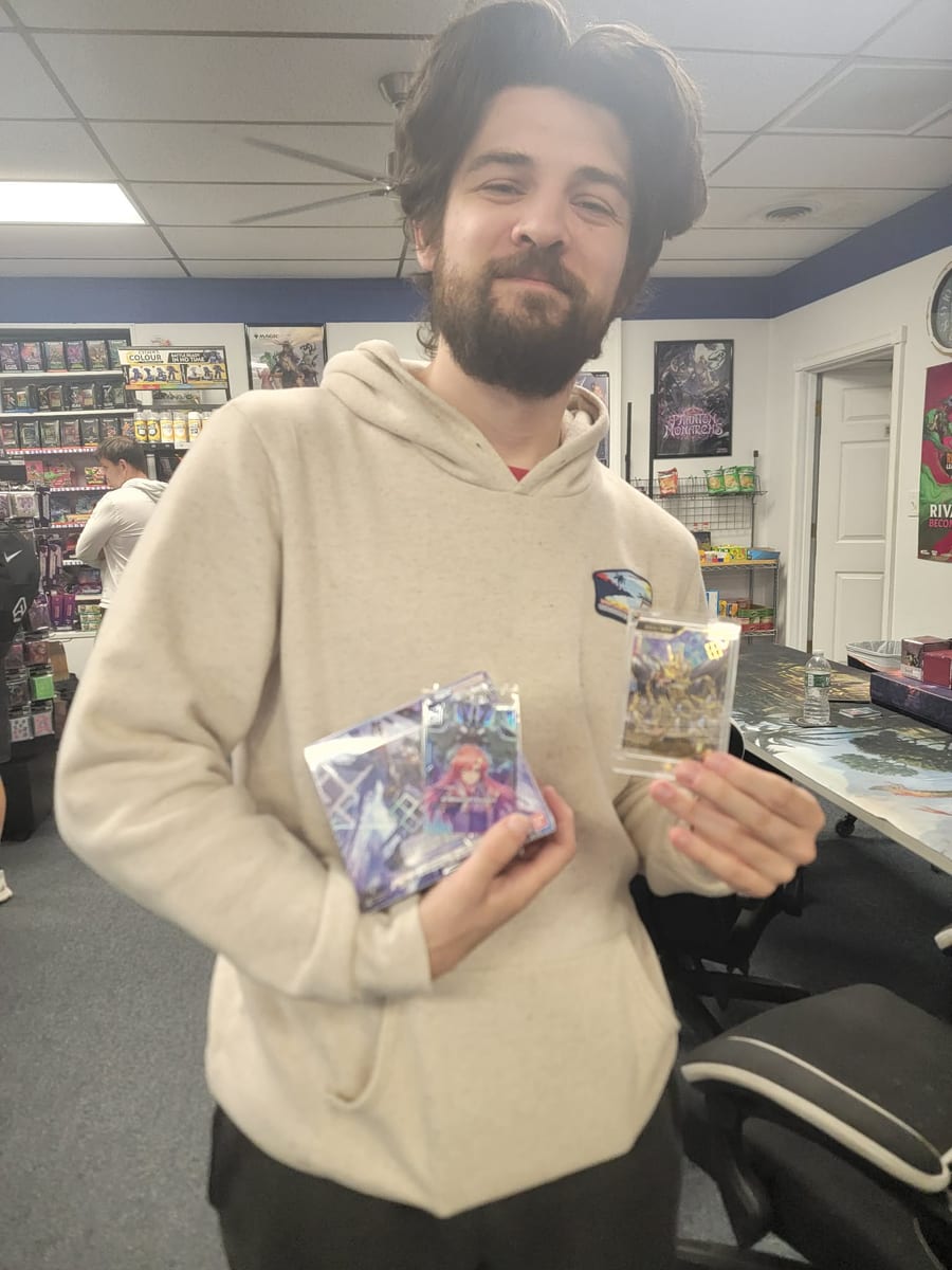 Casey, winner of the Gundam 1st Anniversary Event, holding two sleeved winning cards.